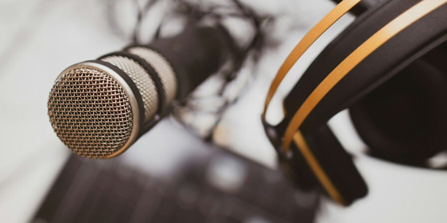 Podcast microphone and headphones hanging above a mixer
